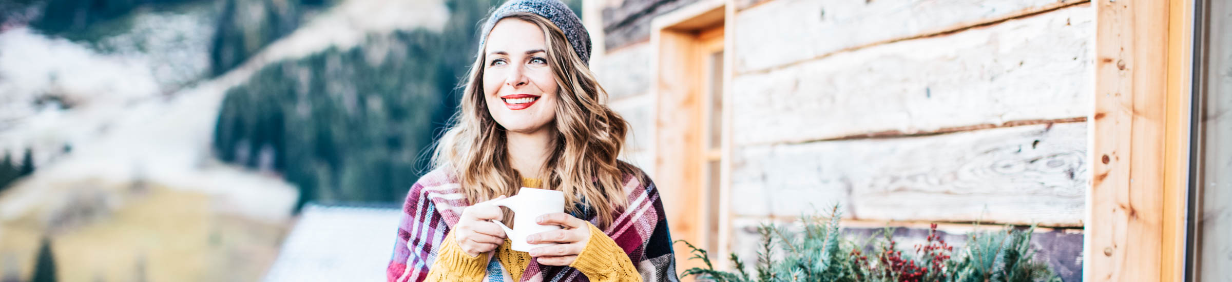 Frau mit Kaffeetasse vor einem der Chalets in Bayern- Header